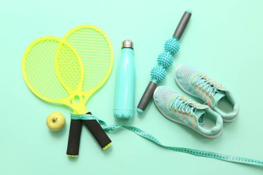 Turkuaz arka planda spor ayakkabıları, elma ve spor ekipmanları