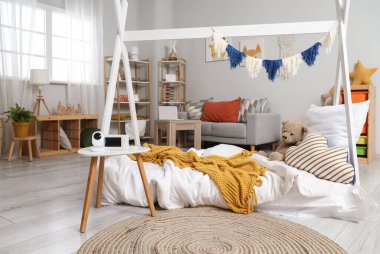 Masada yatak, kanepe ve bebek monitörü olan çocuk odasının içi.