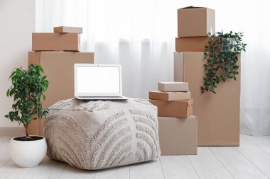 Boş dizüstü bilgisayar pouf üzerinde kutuları odanın penceresinin yakınına taşır