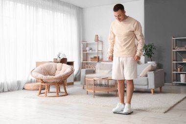 Genç adam ağırlığını evde tartıyla ölçüyor.