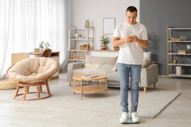 Evde cep telefonu kullanan genç bir adam var.