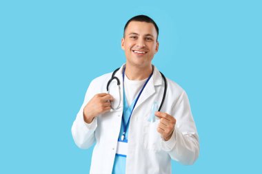 Mavi farkındalık kurdelesine sahip yakışıklı doktor.