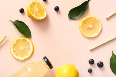 Dilimlenmiş limon, pipet, böğürtlen ve soluk pembe arka planda bir şişe kombu çayından yapılmış çerçeve.