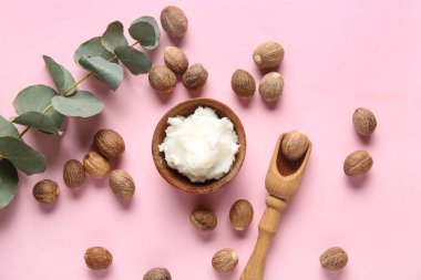 Shea tereyağlı, fındıklı ve pembe arka planda yeşil dallı kase.