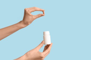 Mavi arka planda hap ve hap kutusu olan kadın elleri