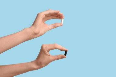 Mavi arka planda hapları olan kadın eller.