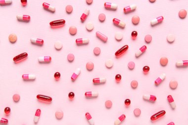 Pembe arka planda farklı haplar, yakın plan.