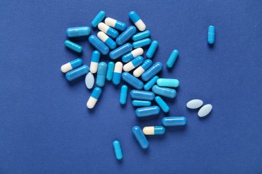 Mavi arka planda farklı haplar, yakın plan.