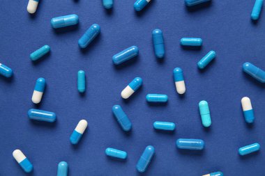 Mavi arka planda farklı haplar, yakın plan.