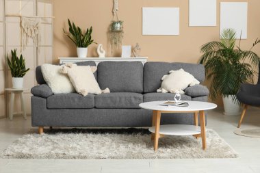 Oturma odasının iç tarafında minderli, koltuklu ve sehpalı rahat bir kanepe.