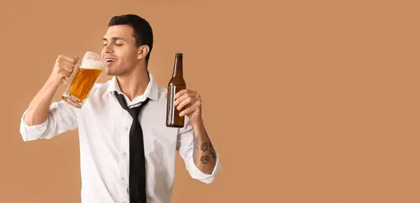 stock image Handsome young businessman drinking beer on brown background with space for text