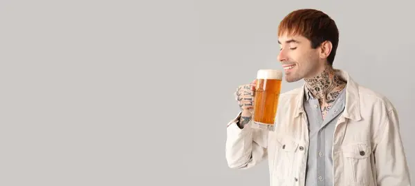 Stock image Young tattooed man drinking beer on light background with space for text