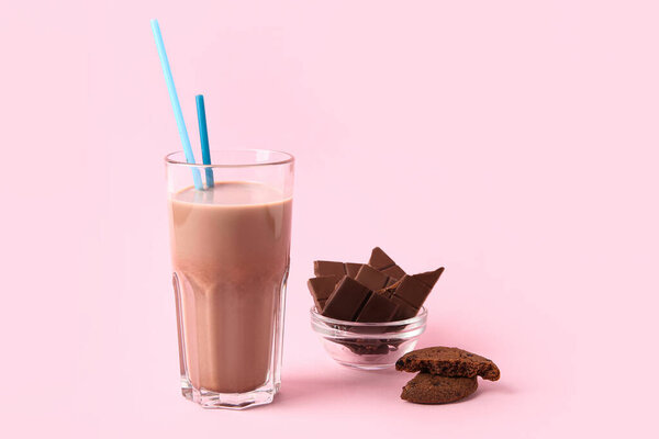 Glass of sweet chocolate milk and tasty cookie on pink background