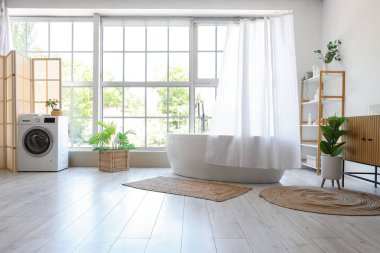 Modern banyonun içinde perde, kilim ve çamaşır makinesi olan küvet.