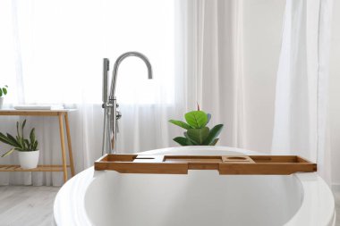 Modern banyonun içinde ahşap tepsiyle perdeli bir küvet.