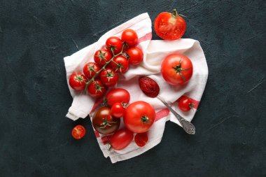 Koyu mavi arka planda bir kaşık macunla beyaz kumaş üzerinde domatesler. Üst görünüm