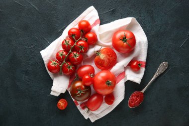 Koyu mavi arka planda bir kaşık macunla beyaz kumaş üzerinde domatesler. Üst görünüm