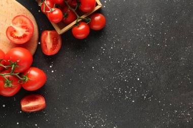 Kesme tahtasında domatesler ve siyah arka planda tepsiler. Yakın çekim.