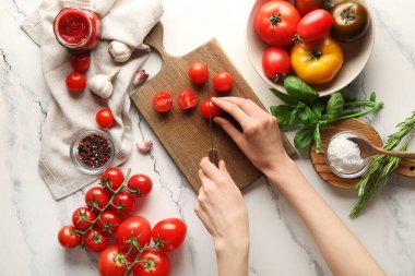 Beyaz arka planda domatesleri kesen kadın eller. Üst görünüm