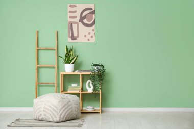 Raflar, merdiven ve pouf yeşil duvarın yanında.