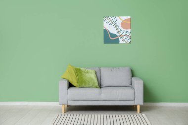 Yastıklı kanepe ve yeşil duvarlı resim