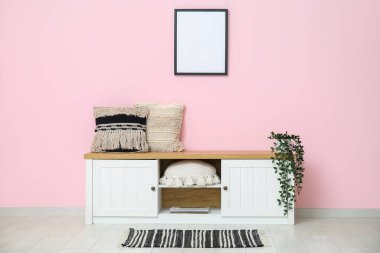 Odadaki pembe duvarın yanında minderleri ve çiçekleri olan bir tabela.