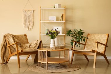 Sandalyeler ve kahve masası ve vazoda yabani çiçekler.