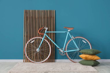 Ekran, yastık ve bisiklet mavi duvarın yanında.