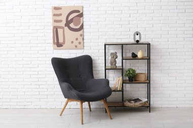 Beyaz tuğla duvarda asılı resim, koltuk ve raf odası