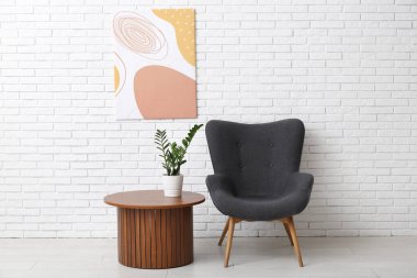 Beyaz tuğla duvara asılı resim, koltuğa ve odadaki kahve masasına.
