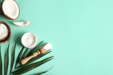 Ahşap kepçe ve turkuaz arka planda palmiye yaprağı ile hindistan cevizi kozmetik kremi kabuğu