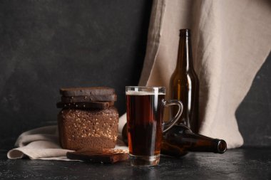 Siyah arka planda bir bardak taze kvass ve ekmek.