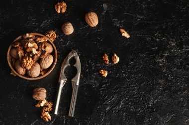 Lezzetli cevizli ahşap kase ve siyah arka planda fındıkkıran.