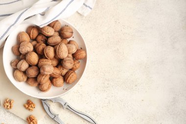 Beyaz arka planda ceviz ve fındık kıracağı olan bir kase.