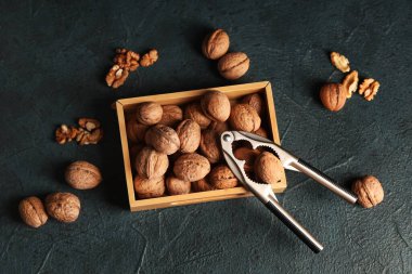Koyu arkaplanda ceviz ve fındık kıracağı olan tahta kutu.