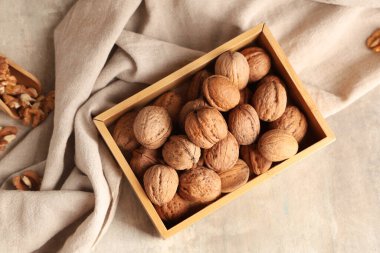 Gri arka planda lezzetli cevizler olan ahşap kutu.