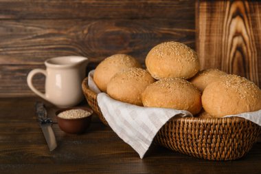 Tahta arka planda susam tohumlu bir tabak taze çörek.