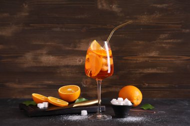 Bir bardak Aperol Spretz kokteyli. Siyah masada meyve ve şeker.