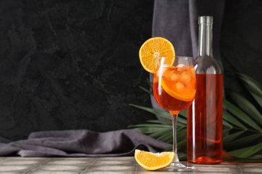 Bir bardak Aperol spreyli kokteyl ve gri fayans masasında palmiye yaprağı.