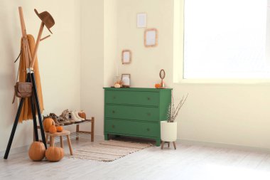 İçinde balkabakları, elbise askılığı, çekmece ve ayakkabı standı olan rahat bir salon.