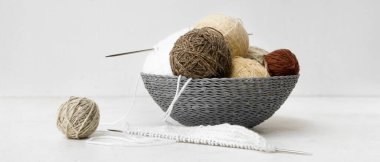 İplikli sepet ve beyaz arka planda örgü iğneleri.