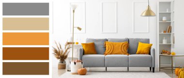 Gri kanepe, standart lamba ve balkabağı olan bir sonbahar salonu. Farklı renk desenleri