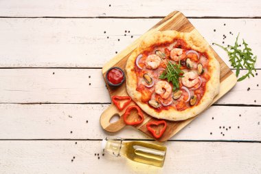 Hafif ahşap zemin üzerinde lezzetli deniz ürünleri pizzası olan bir pano.