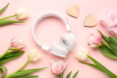 Modern kulaklıklı kompozisyon, tahta kalpler ve pembe arka planda güzel lale çiçekleri.