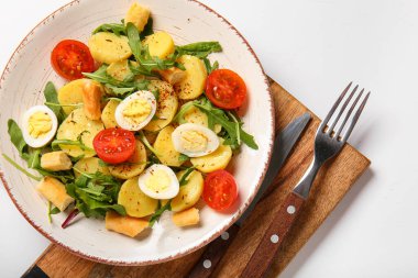 Beyaz arka planda yumurta ve domatesli lezzetli patates salatası.