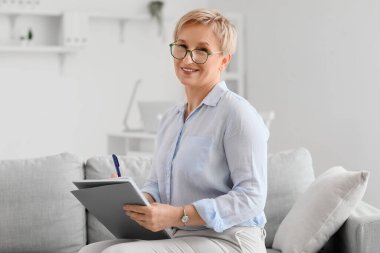 Not defteriyle ofiste oturan olgun bir psikolog.