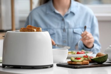 Kadın, modern tost makinesi ve lezzetli sandviçlerle kahvaltı yapıyor.
