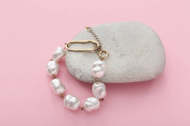 Pembe arka planda inci bileziği olan taş.