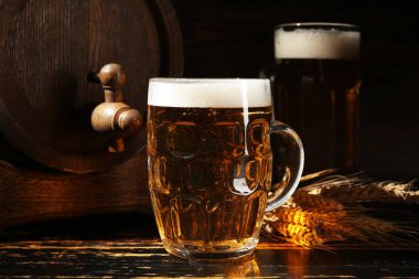 Bir bardak soğuk bira ve arka planda ahşap fıçı.