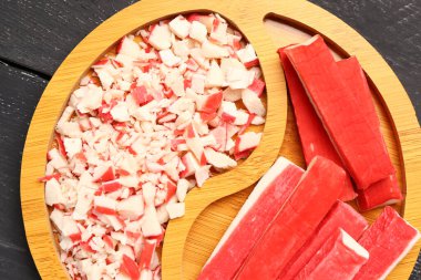 Koyu ahşap arka planda lezzetli yengeç çubukları olan tabak, yakın plan.